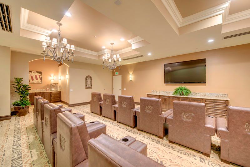 A luxurious home theater room with comfortable recliner chairs and an elegant chandelier.