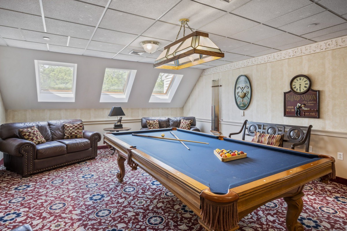 A cozy game room featuring a pool table, comfortable seating, and skylight windows.