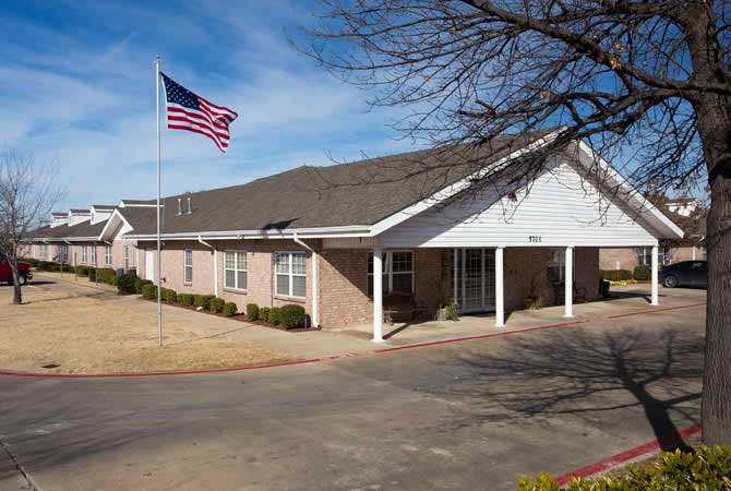 A suburban building with an American flag waving in the foreground on a clear day.