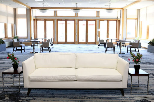A modern cream-colored couch placed in a spacious lounge area with large windows.