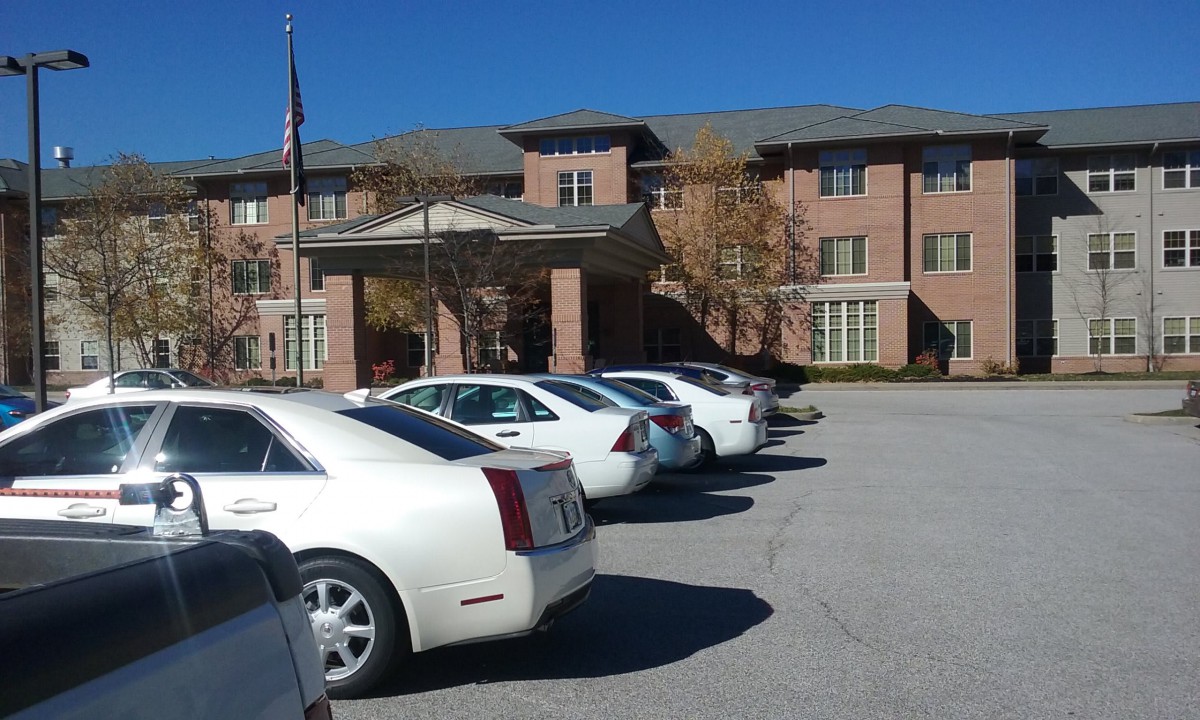 A row of parked cars in front of a brick building on a sunny day.