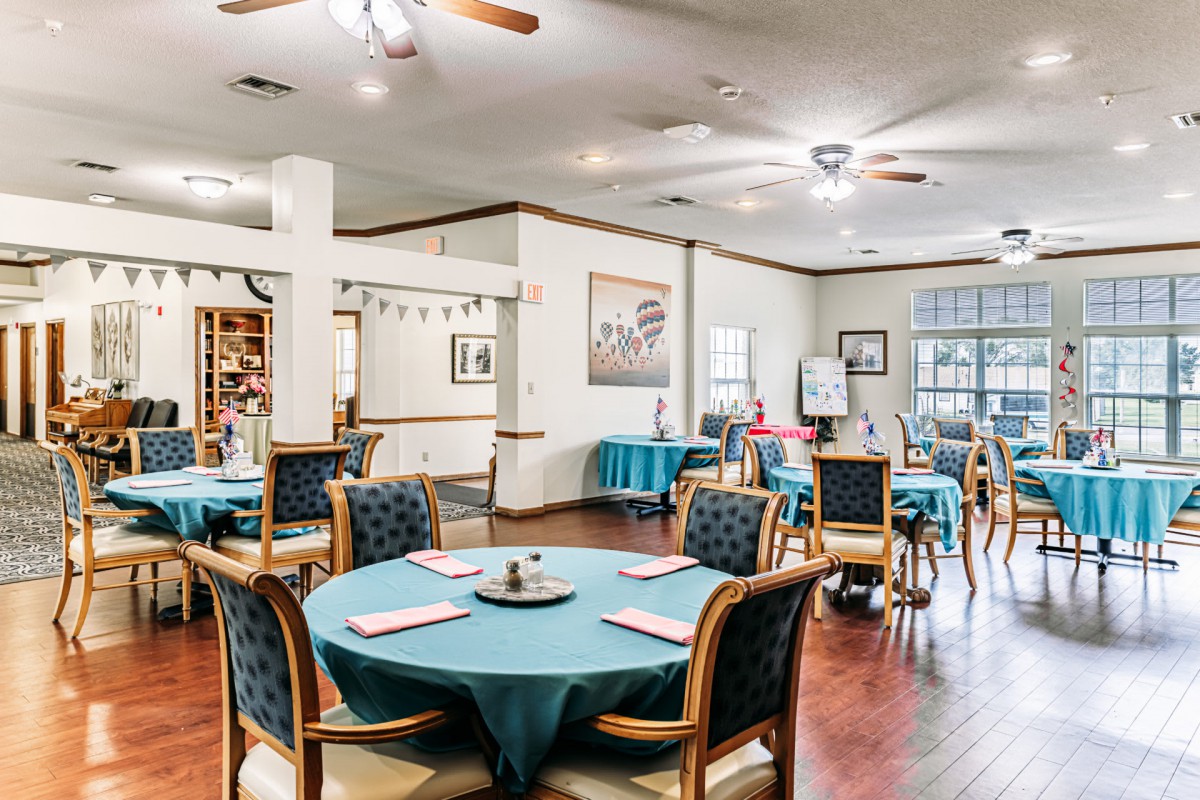 A cozy dining area with several tables and chairs arranged on a wooden floor, featuring decorative elements.