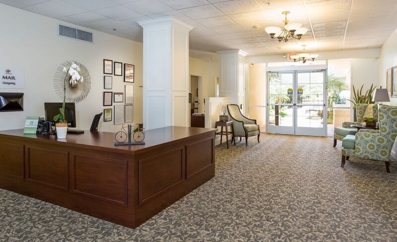 A well-lit reception area featuring a wooden desk, comfortable seating, and decorative lighting.