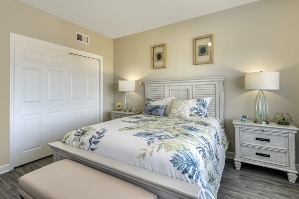 A cozy bedroom with a floral-patterned bedspread, complemented by matching pillows, nightstands, and lamps.