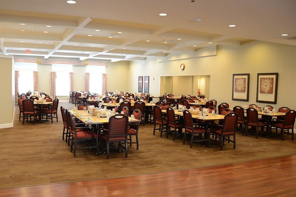 An empty dining hall with neatly arranged tables and chairs, ready for an event.