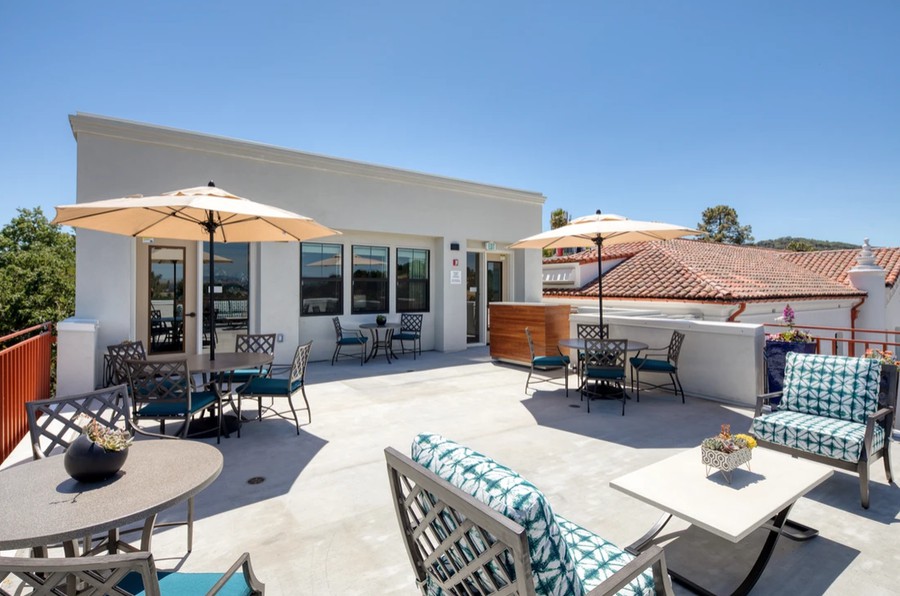 A modern outdoor patio with umbrellas and furniture on a sunny day.