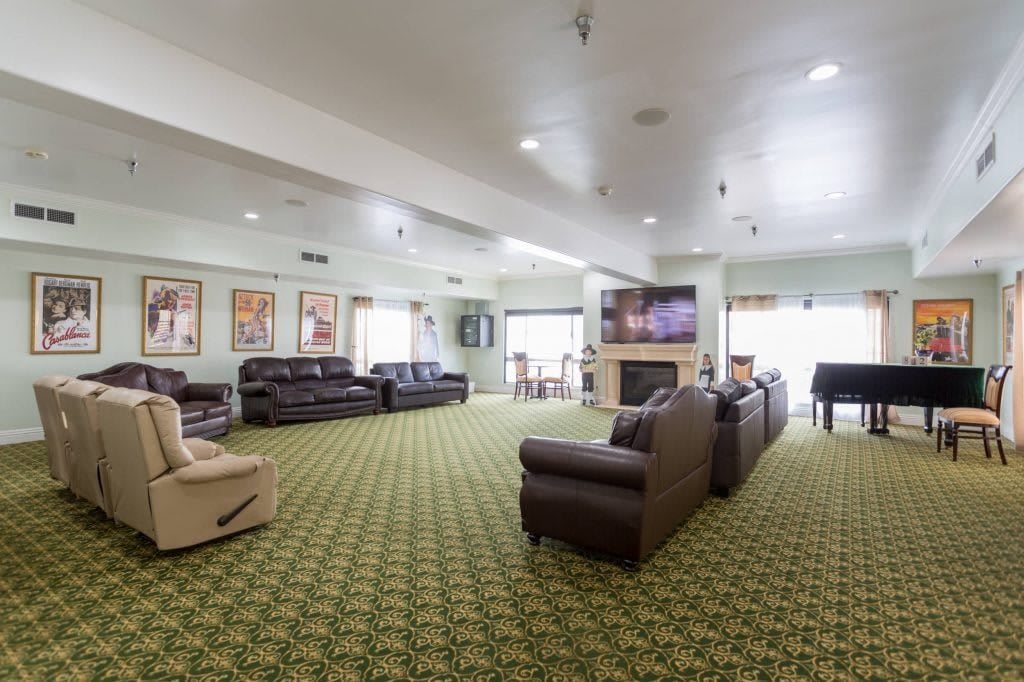 A spacious living room with multiple sofas, a television, and a fireplace, featuring a patterned carpet.