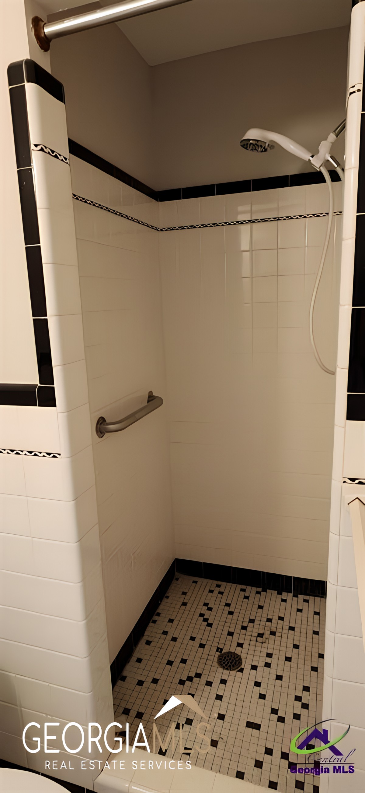 A tiled shower area with a grab bar installed on the wall.