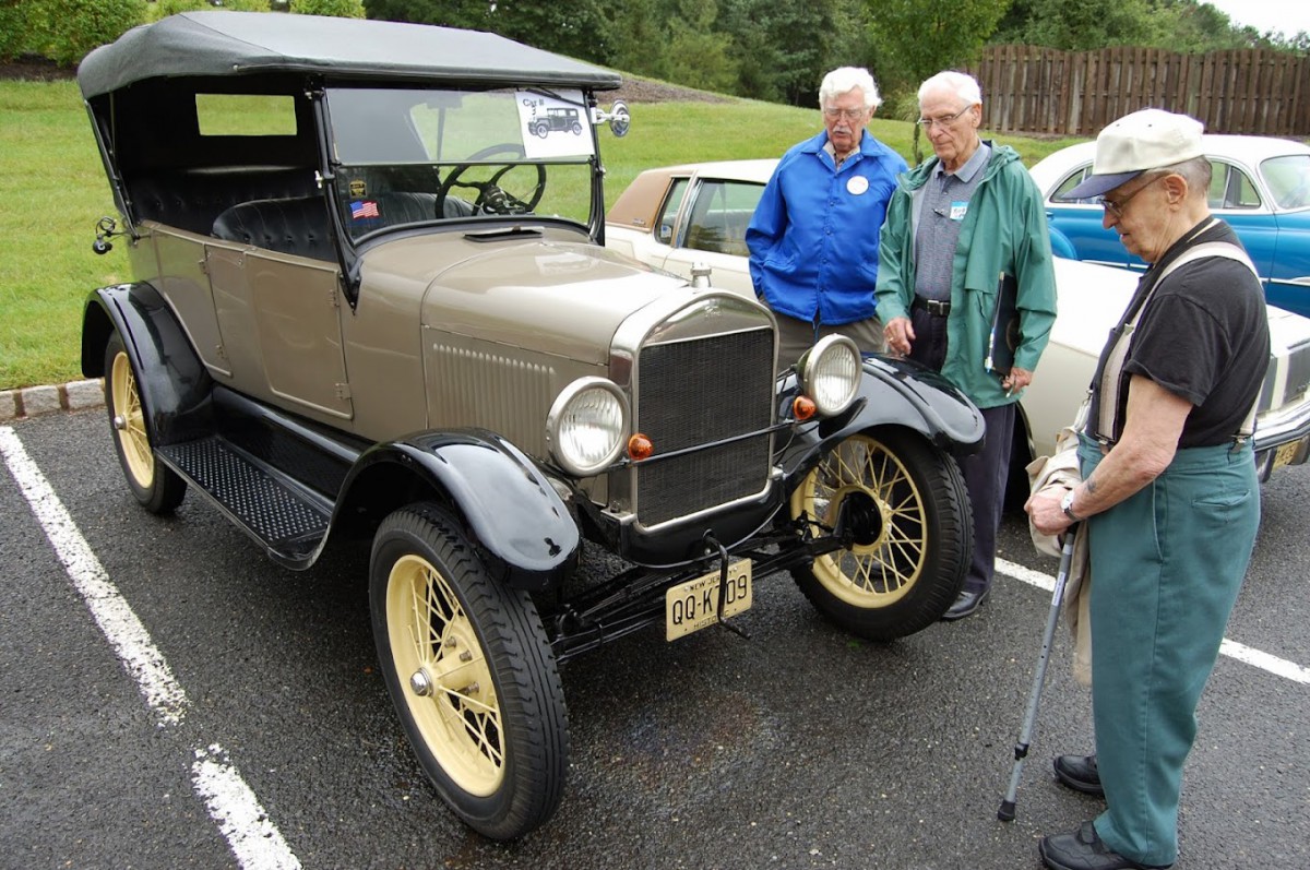 A vintage car displayed at a car show with two people admiring it.
