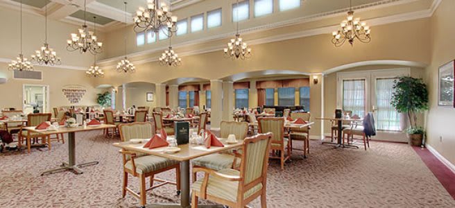 A well-lit dining area with elegant chandeliers and neatly arranged tables and chairs.