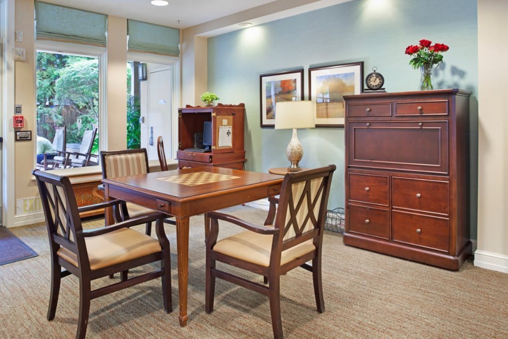 A well-furnished office space featuring a wooden table, chairs, and a cabinet with decorative elements.