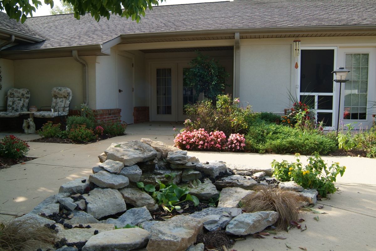 A single-story house with a landscaped front yard featuring a rock garden and surrounding greenery.