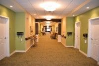 A well-lit corridor with green walls and carpeted flooring.