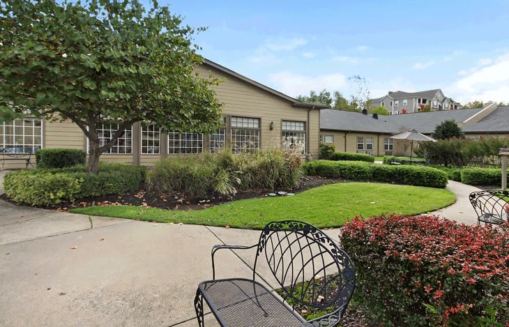 A serene outdoor area featuring a building, garden, and bench.