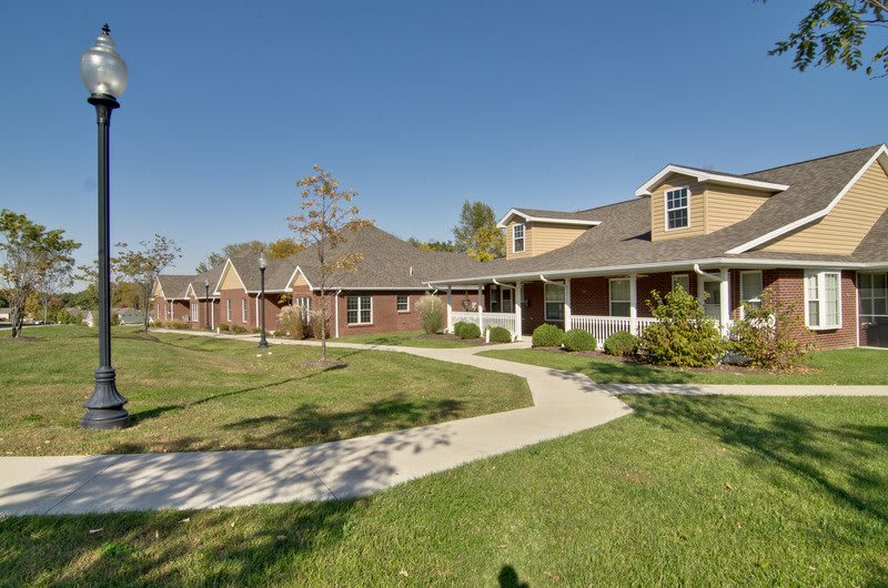 A row of suburban houses with a well-maintained lawn and winding pathway under a clear blue sky.