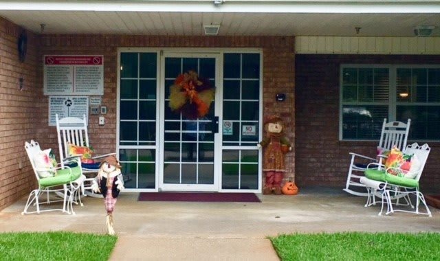 A building entrance adorned with fall decorations, including a wreath and scarecrow.