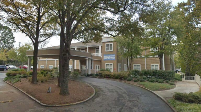 A view of a building entrance with a circular driveway and surrounding trees.