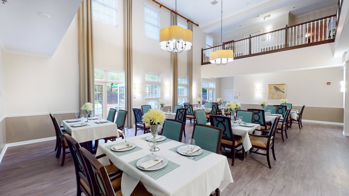 An elegant dining room with neatly arranged tables and chairs, adorned with chandeliers and tasteful decor.