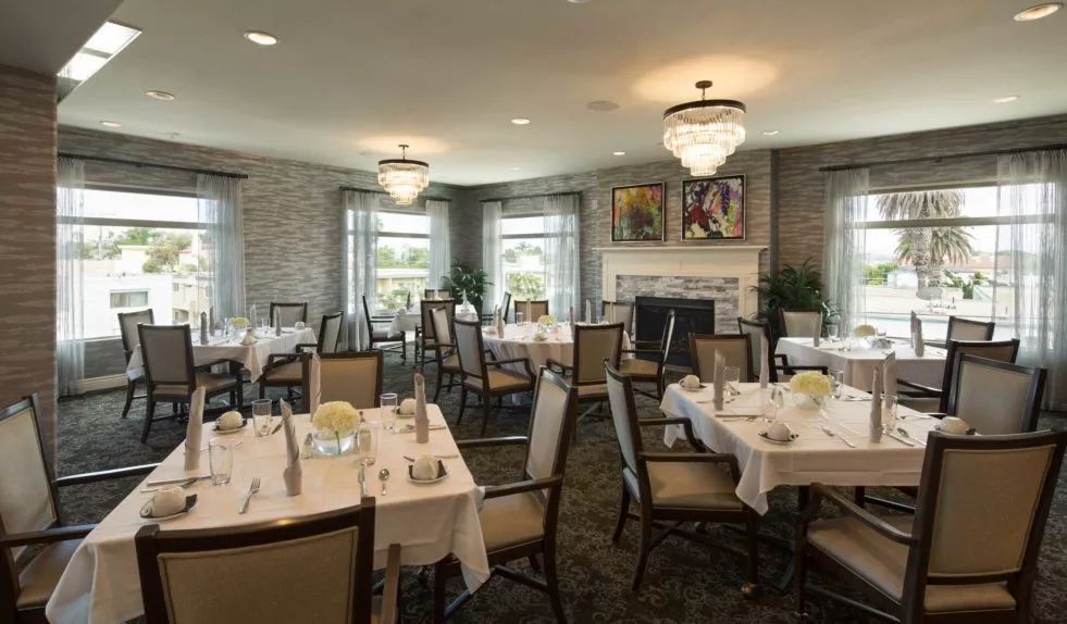 An elegant dining room with neatly arranged tables and chandeliers.
