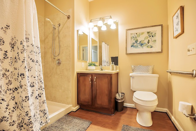 A modern bathroom featuring a shower, vanity with mirror, and toilet.