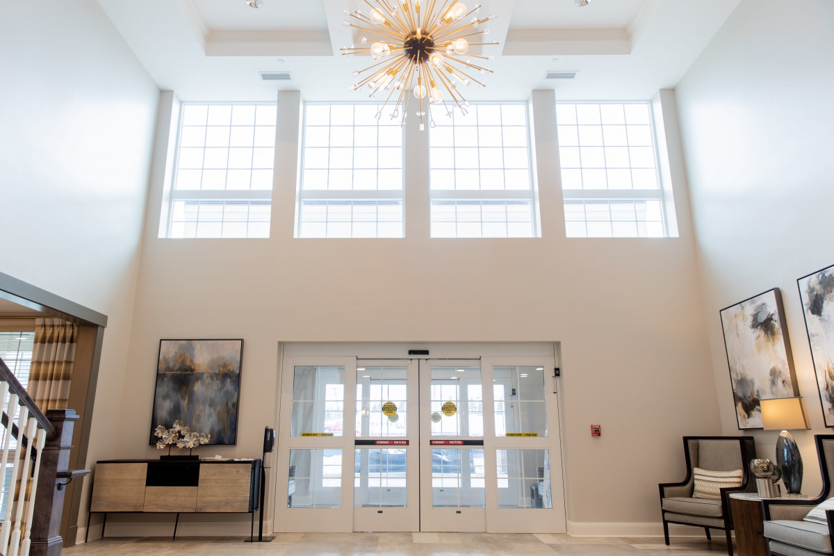 A modern lobby with large windows, a striking chandelier, and elegant decor.