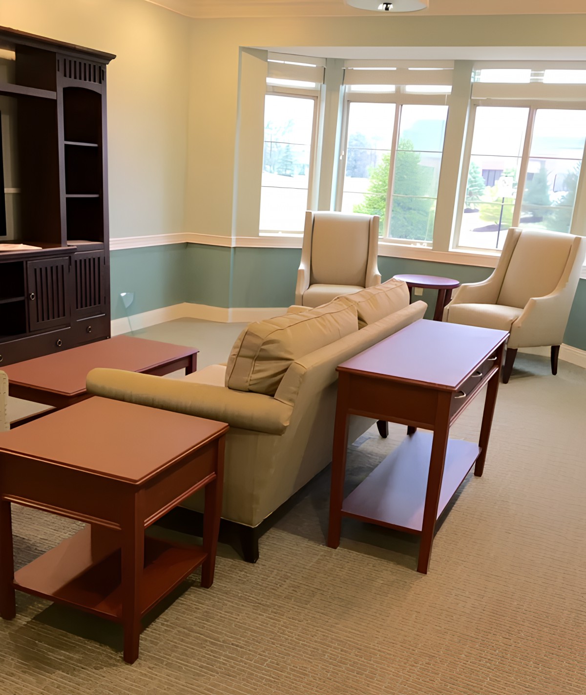 A cozy living room setup with a sofa, chairs, and tables near a large window.