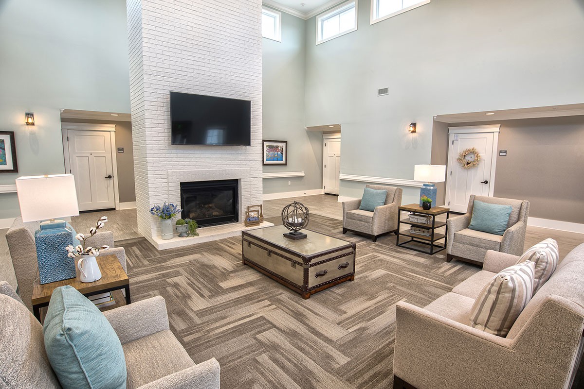 A modern living room with a fireplace, stylish seating, and a large flat-screen TV.