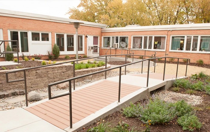 A brick building with a ramp entrance, surrounded by autumn foliage.