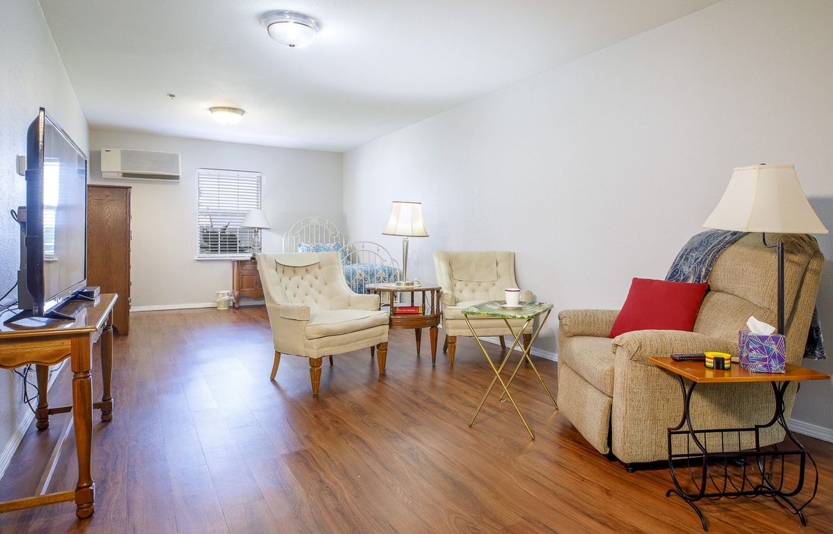 A cozy living room with armchairs, a sofa, and wooden flooring.