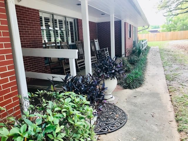 A cozy front porch with rocking chairs and lush greenery.
