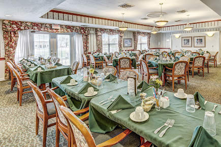 An elegant dining room with neatly set tables and green tablecloths.