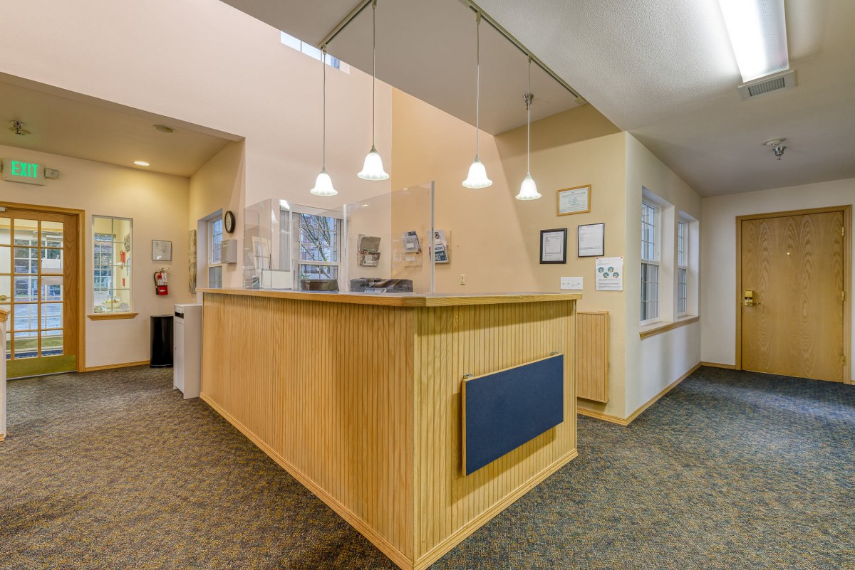A modern reception desk with wood paneling and pendant lighting in an office lobby.