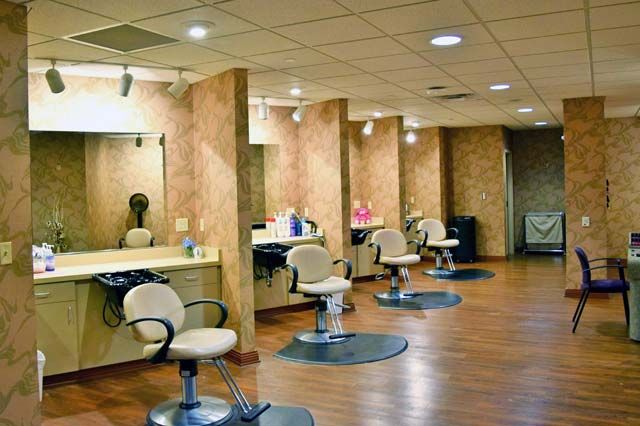An empty hair salon with chairs and mirrors lined up against the walls.