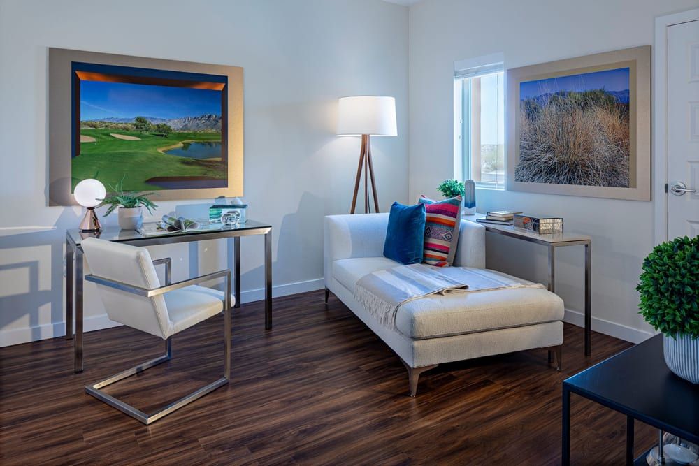 A modern living room with stylish furniture and artwork, featuring a chaise lounge and a desk.