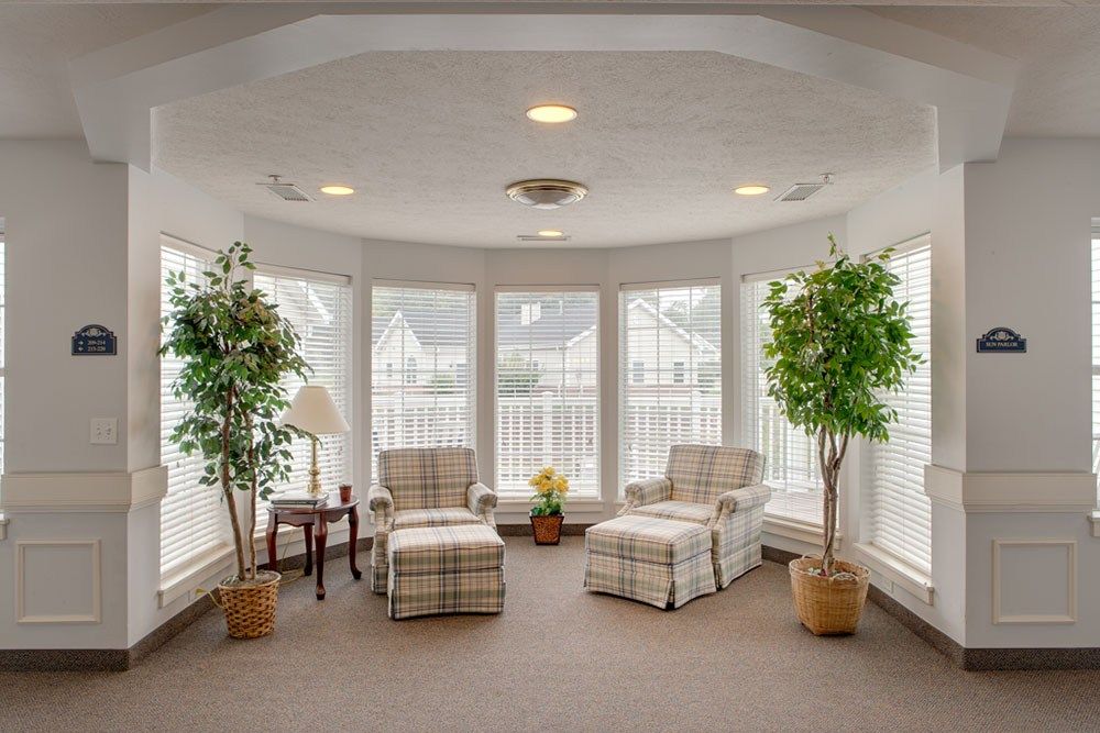 A cozy living area with two armchairs, large windows, and potted plants.