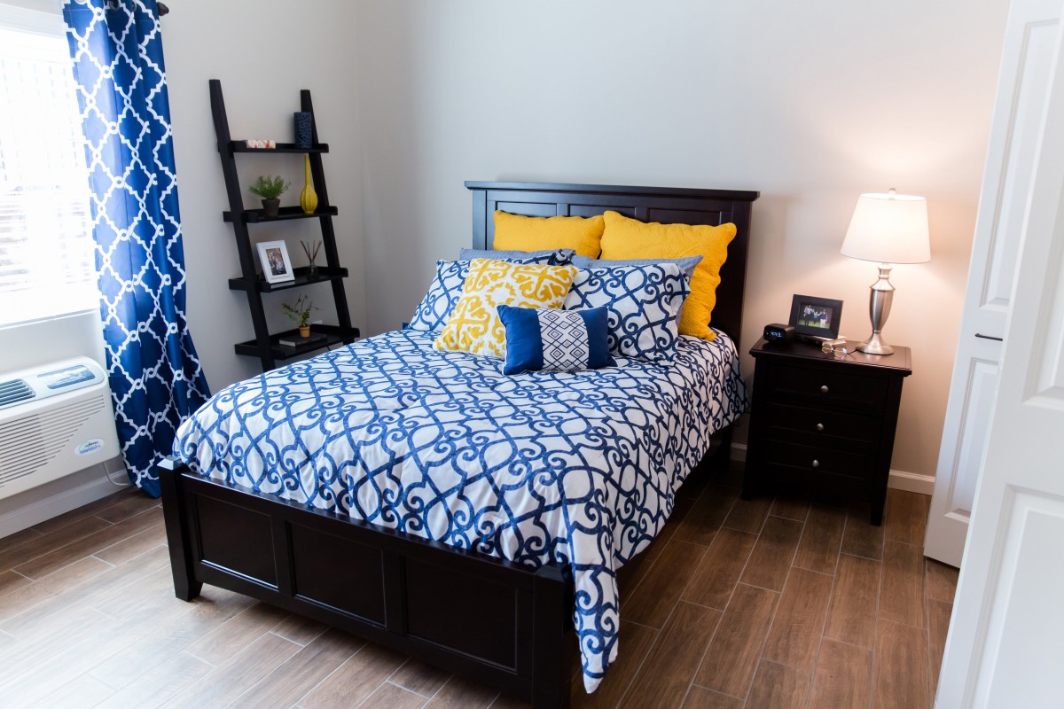 A cozy bedroom with a dark wooden bed, colorful pillows, and a stylish bedding set.