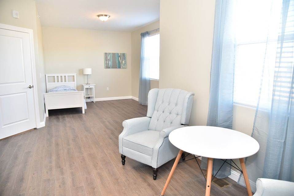 A minimalist bedroom with a cozy armchair, round table, and bed.
