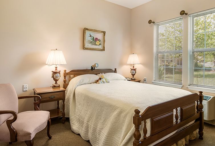 A cozy bedroom with a wooden bed, nightstands, and two lamps by the window.