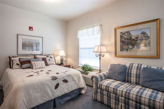 A cozy bedroom with a bed, sofa, and soft lighting.