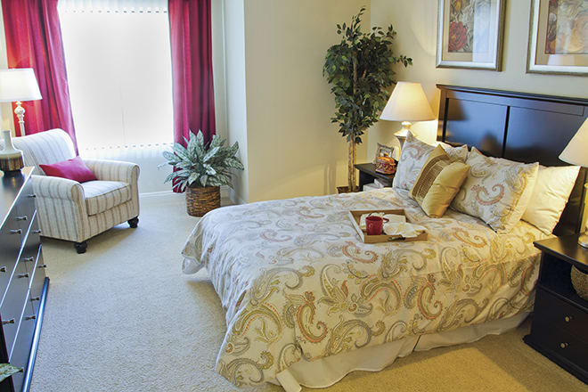 A cozy bedroom with a comfortable bed, decorative pillows, and elegant furnishings.