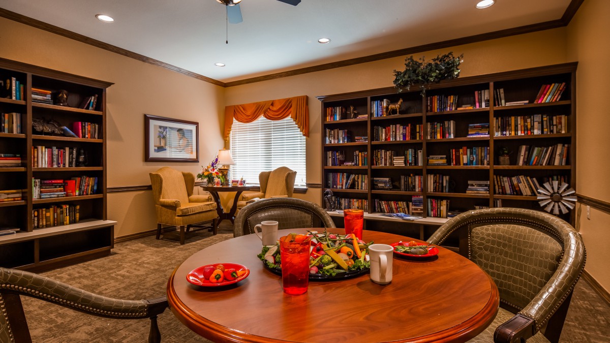 A cozy reading room with a table set for refreshments and a bookshelf filled with books.