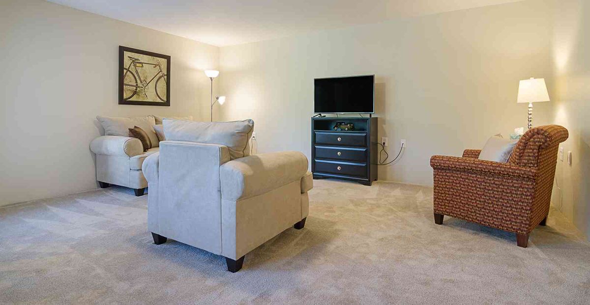 A cozy living room with a television, armchair, and warm lighting.