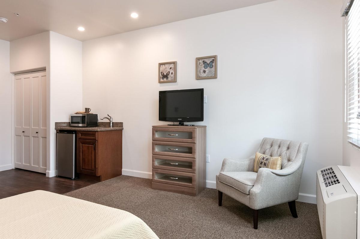 A modern bedroom featuring a television, cozy chair, and minimalist decor.
