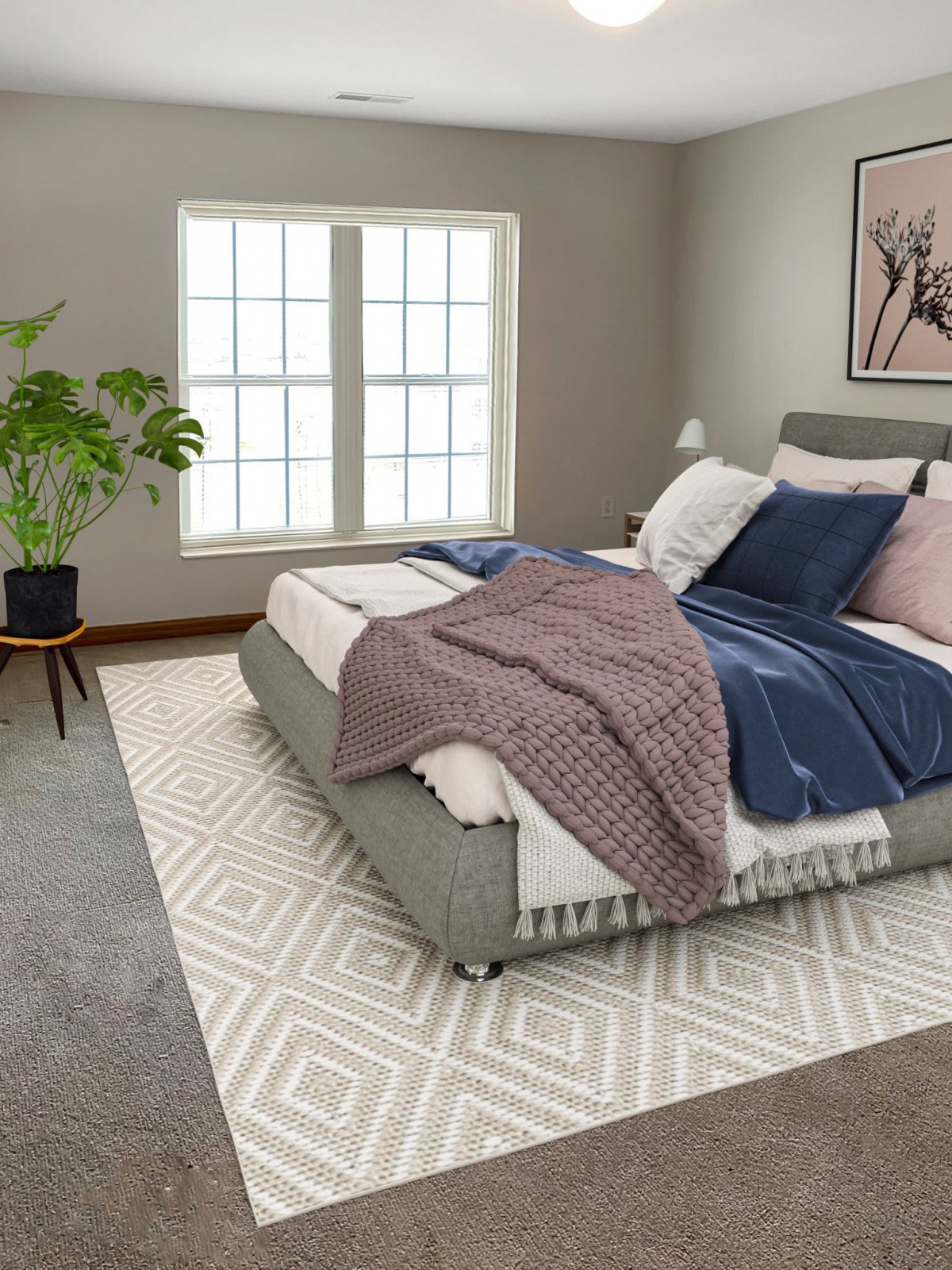 A modern bedroom featuring a neatly-made bed with pillows and throws, a large window, a house plant, and a patterned rug.