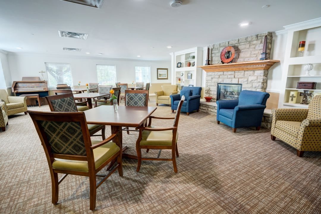 A cozy living room with comfortable seating, a fireplace, and tables for gathering.