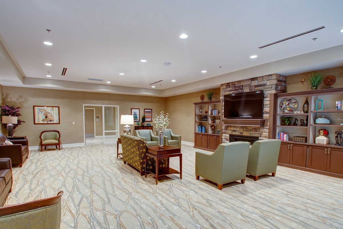 A cozy living room with comfortable seating, a television above a fireplace, and elegant decor.