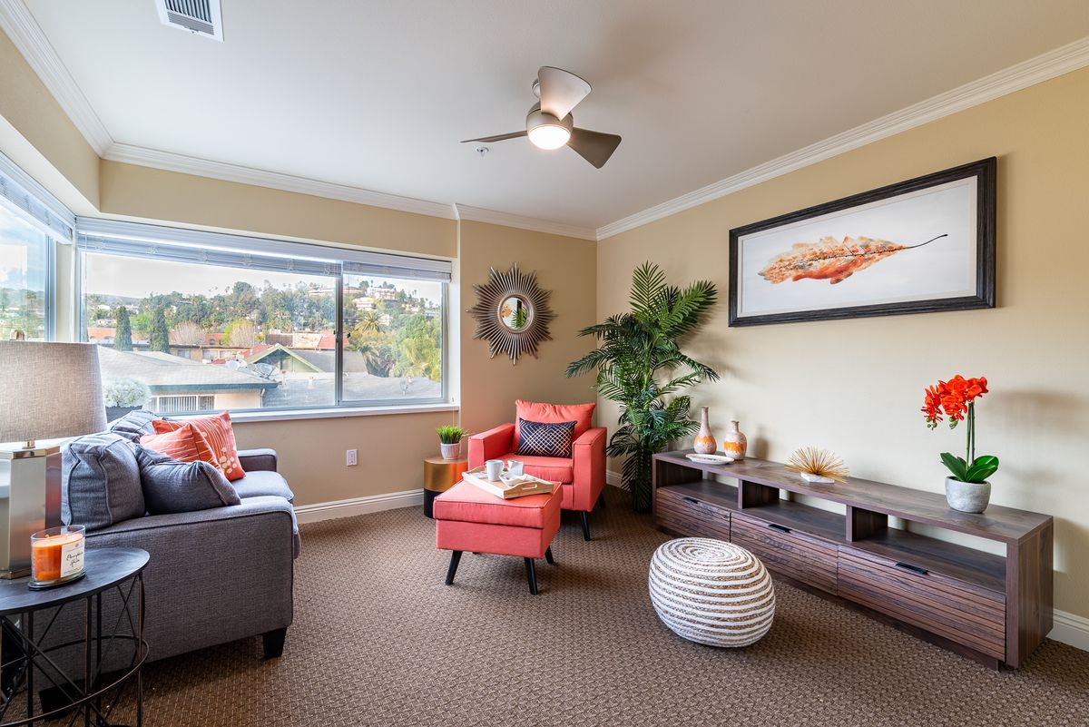 A cozy living room with modern decor featuring a red armchair, large window, and natural lighting.