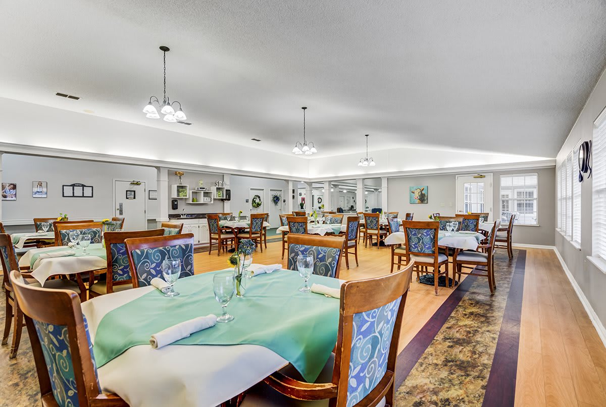 A spacious dining area with neatly arranged tables and chairs under soft lighting.