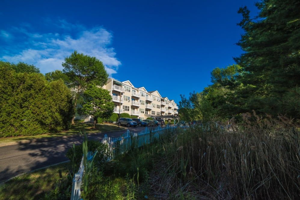 A scenic view of apartment buildings surrounded by lush greenery under a clear blue sky.