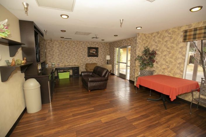 A cozy living room with wooden flooring, featuring a sofa, table, and television.